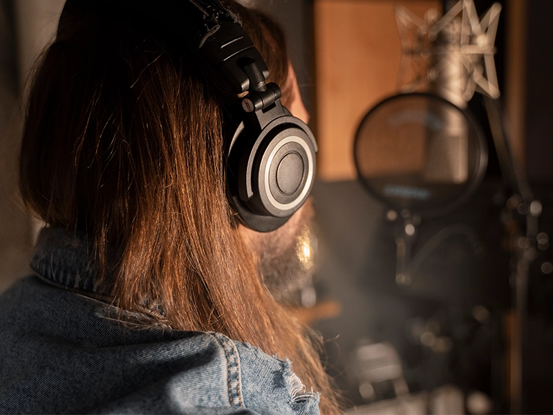 A woman singing in the studio with a headphone on his ears By Music School In Oak.