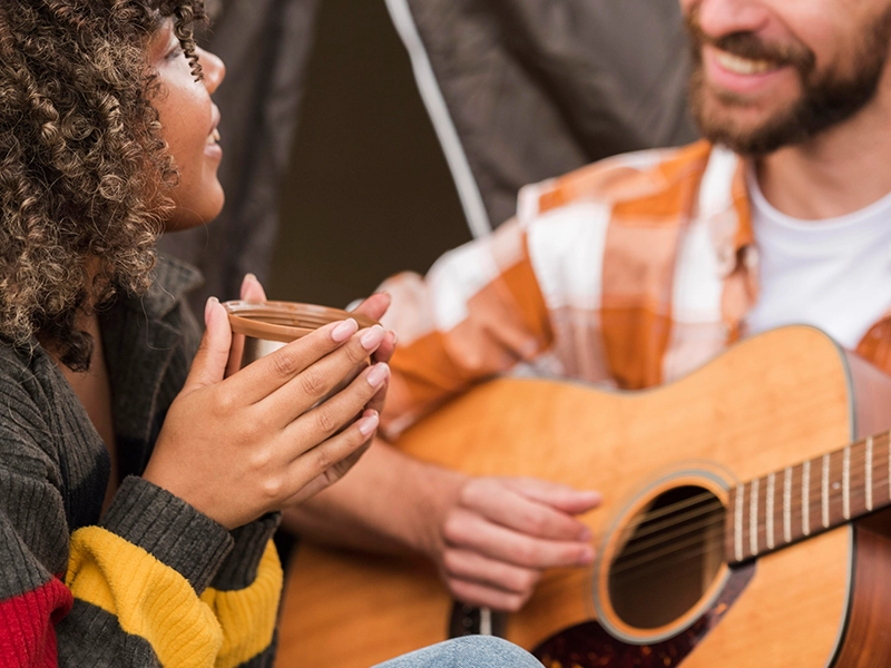 Couple playing guitar while camping outside By Music School In Oak Park.