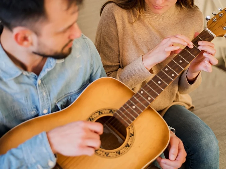 High angle of guitar teacher tutoring student at home By Music School In Oak Park.